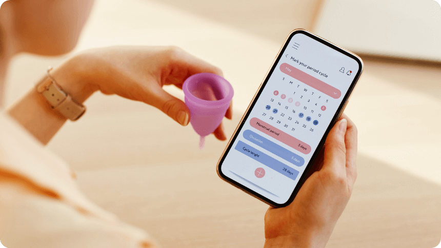 月経カップとスマホのカレンダーを手に持つ女性