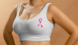 乳がんの啓発運動のシンボルマークであるピンクリボンを胸元付けた女性の上半身
