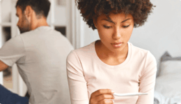 後ろで彼が背中を向けているときに妊娠検査薬を見つめる女性