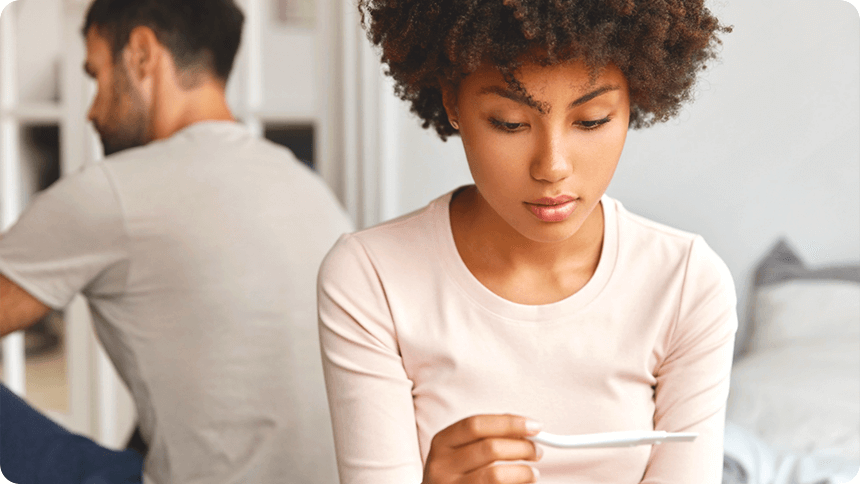 後ろで彼が背中を向けているときに妊娠検査薬を見つめる女性