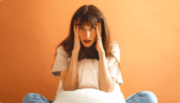 ベッドの上で不安そうに頭を抱える女性
