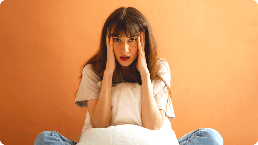 ベッドの上で不安そうに頭を抱える女性