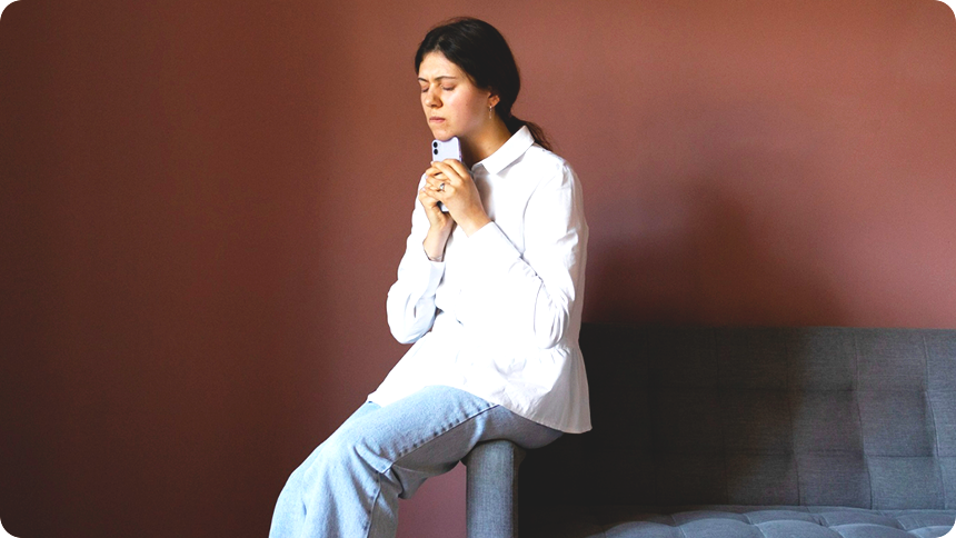 50代くらいの女性が胸元でスマホを握りしめ何か不安そうに考えている姿