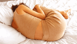 ベッドの上でうずくまる女性