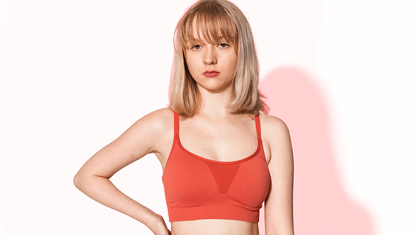 赤いブラトップを着た女性が無表情でこちらを見る様子。体型や下着に関する悩みを連想させるシーン