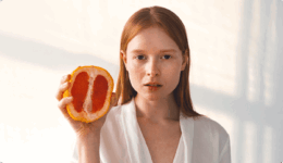 どこか不安そうな女性がグレープフルーツを握りしめる様子