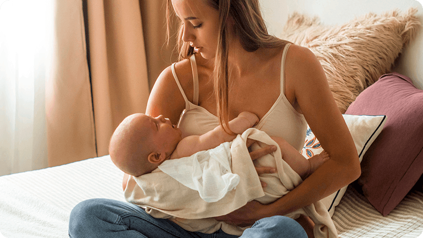 お母さんが新生児をキャミソール姿であやす様子