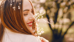 春の陽射しの中で花を抱きしめ、幸せそうに微笑む女性。自然体で恋を楽しむ姿。