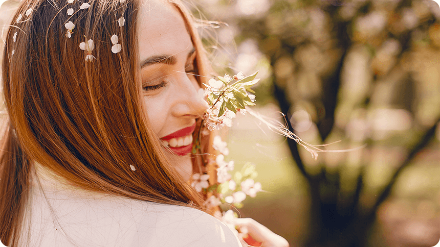 春の陽射しの中で花を抱きしめ、幸せそうに微笑む女性。自然体で恋を楽しむ姿。