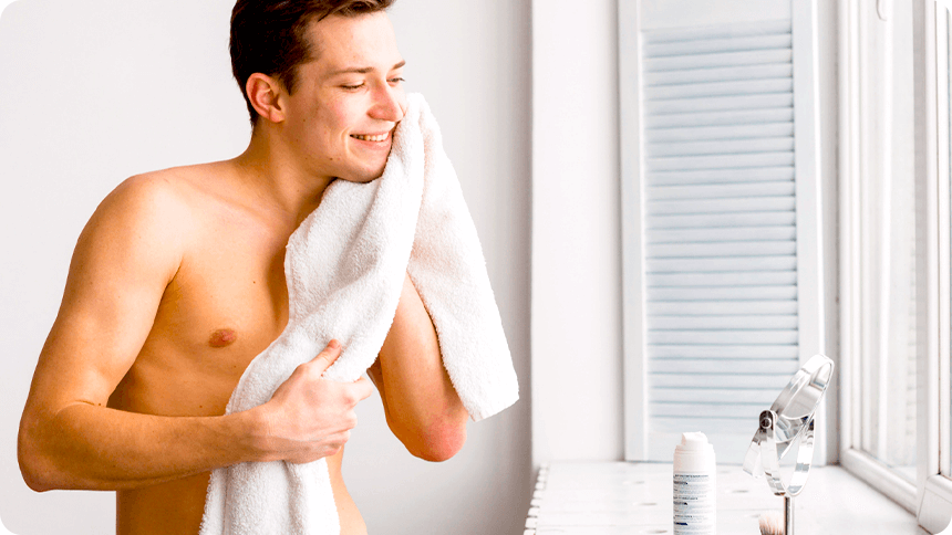 清潔な白い部屋で、シャワー後に身だしなみを整える男性