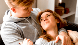 ソファで寄り添いながら見つめ合うカップル。穏やかで温かい愛情を感じさせる瞬間。