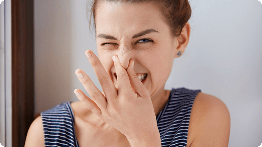 若い女性が強い匂いを避けるように鼻をつまんでいる。ニオイに嫌悪感を示す表情