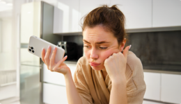 不機嫌そうにスマホを持ち頬杖をつく女性