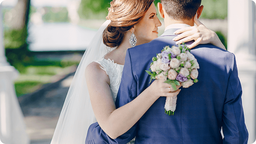 花嫁が新郎の肩に手を添えながら寄り添うシーン。ブーケを手にした幸福感のある後ろ姿