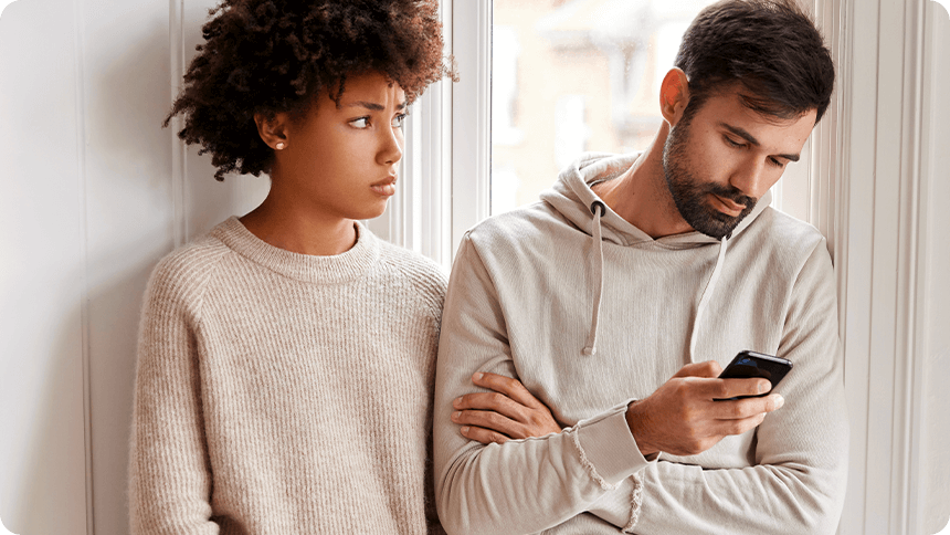 窓辺で、スマホを見続ける男性と困った表情で見つめる女性