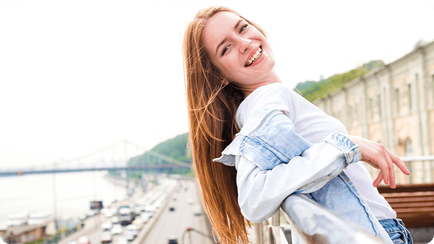 屋外の手すりにもたれ、振り返って笑う女性