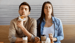 テーブルに飲み物を置き、並んで座る男女