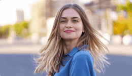 街中で風に髪をなびかせながら微笑む女性