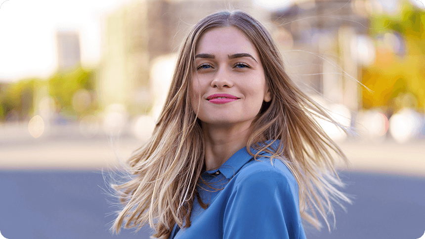 街中で風に髪をなびかせながら微笑む女性