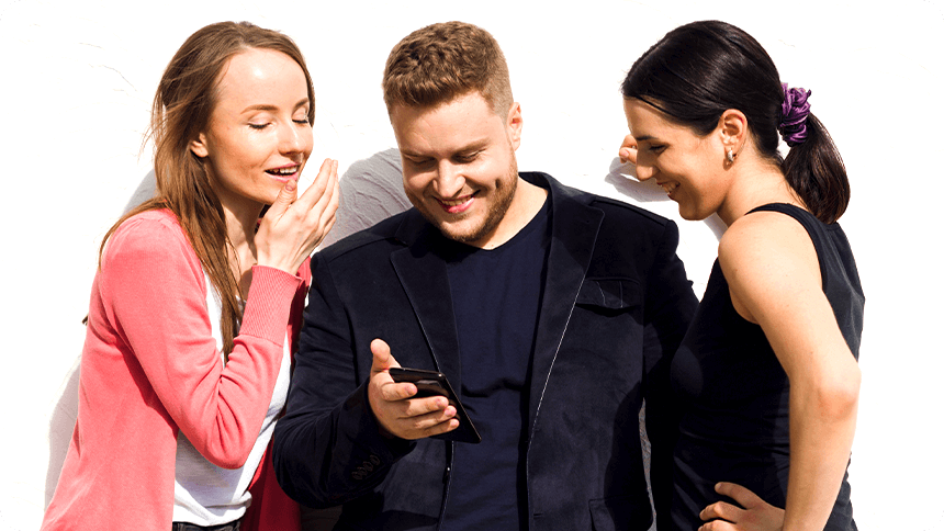 女友達に囲まれてスマホを見ながら楽しそうに笑う男性