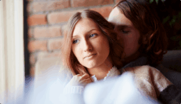 寄り添う男性の腕の中で、どこか不安そうな表情を見せる女性