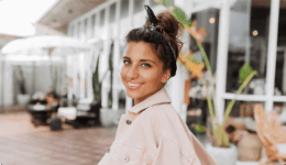 柔らかな光の中で、自然体な笑顔を見せる女性。誰かと競う優越感ではなく、自分自身の在り方を大切にしている、自律した大人の女性の軽やかさと自信を感じさせる一枚