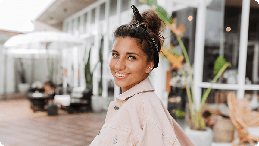 柔らかな光の中で、自然体な笑顔を見せる女性。誰かと競う優越感ではなく、自分自身の在り方を大切にしている、自律した大人の女性の軽やかさと自信を感じさせる一枚