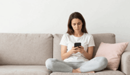 、疲れた様子で物思いにふけりながらスマートフォンを眺める女性