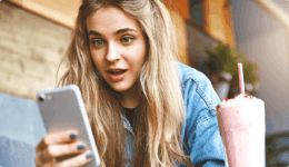 驚きの表情でスマートフォンを覗き込む女性