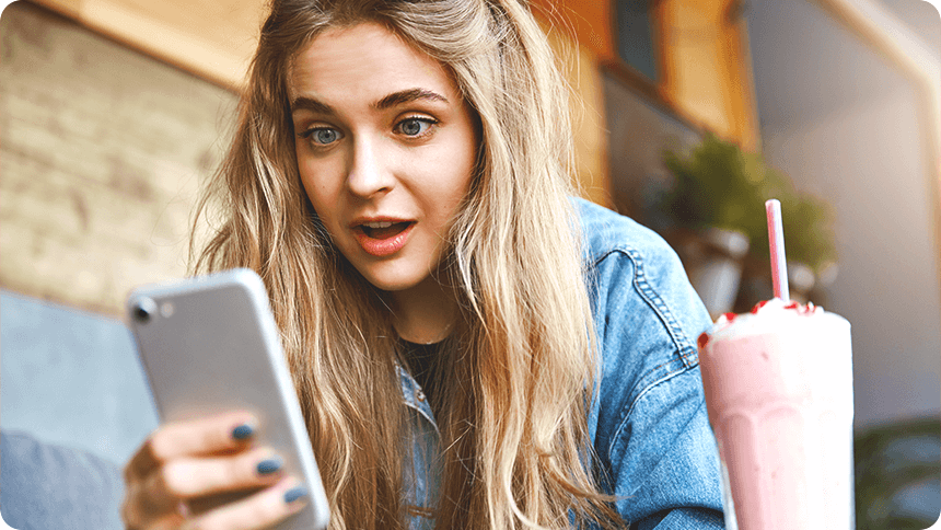 驚きの表情でスマートフォンを覗き込む女性