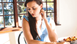 明るいカフェでうつむき加減の女性。デート中の緊張や戸惑いを感じさせる表情。