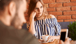 カフェで、スマホを見る男性を前に不満そうな表情の女性