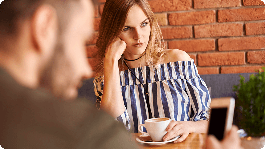 カフェで、スマホを見る男性を前に不満そうな表情の女性