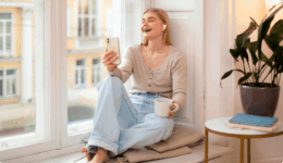 窓辺のリラックスした空間で、笑顔でスマホを見つめる女性