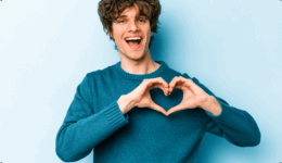 青い背景の前で手でハートを作り笑顔を見せる男性