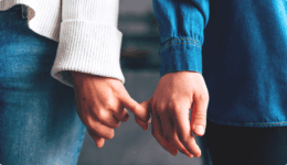 デニムの袖から見えるカップルが指を絡めてつなぐ手元