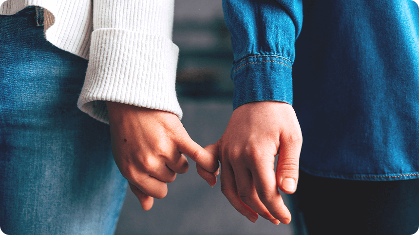 デニムの袖から見えるカップルが指を絡めてつなぐ手元