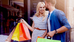 街中で買い物を楽しむカップル。男性がショッピングバッグを持ち、笑顔で会話する様子。