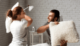 部屋の中で枕投げを楽しむカップル。リラックスした雰囲気の中でじゃれ合う様子