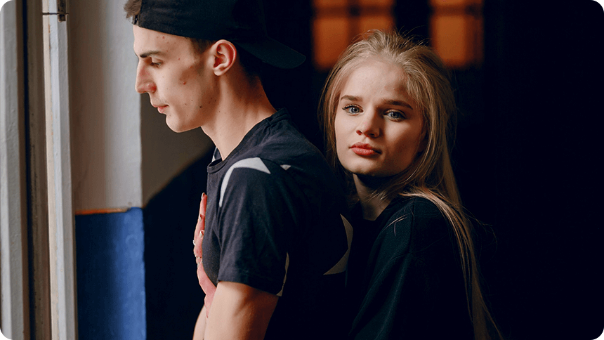 男性の背後から、女性が不安げな表情で抱きしめる