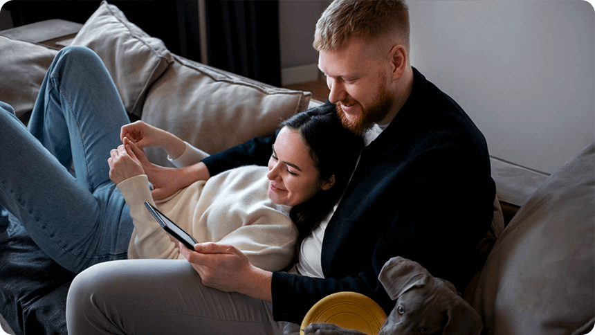 ソファでくつろぎながら、タブレットを一緒にのぞき込むカップル