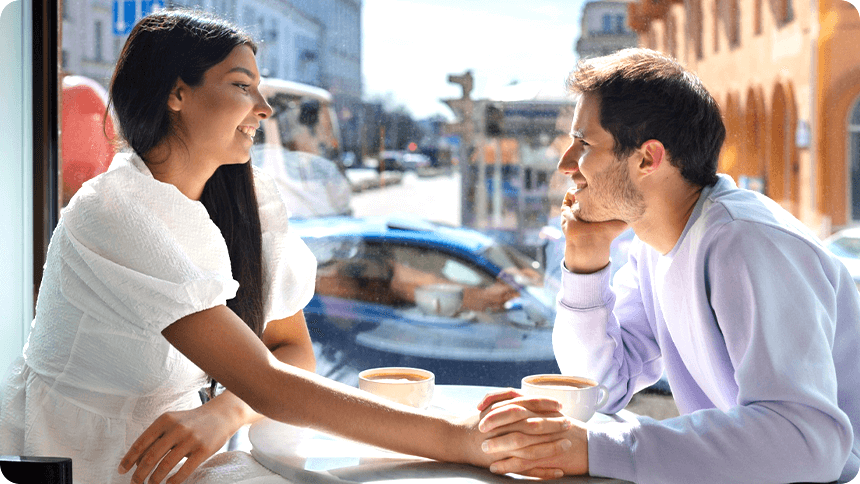 窓際の席で、女性の手を握りじっと彼女の目を見つめる男性