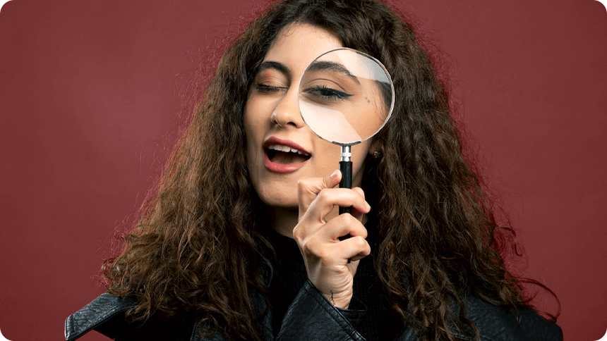 ルーペで目元を大きく見せ、こちらを怪しむように見せる女性