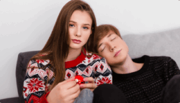 ソファで、眠る男性にもたれられ無表情で座る女性