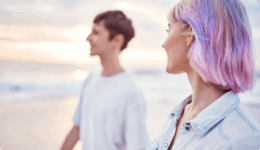 海辺で向かい合い、会話をしている若い男女の横顔