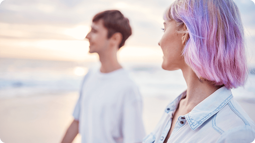 海辺で向かい合い、会話をしている若い男女の横顔