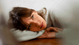 机の上に、腕を枕に浮かない表情でうなだれる女性