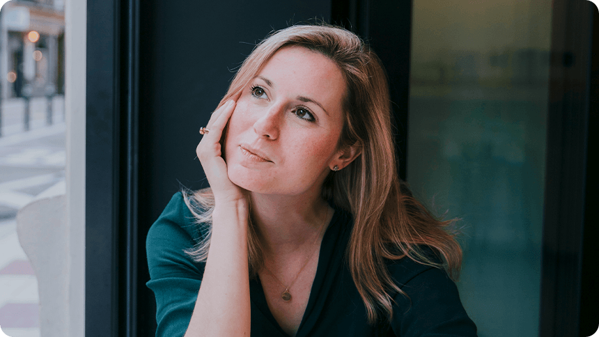 カフェで頬杖をつきながら考え事をしている女性