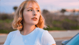 夕暮れの屋外で横を向いて遠くを見つめるブロンドの女性