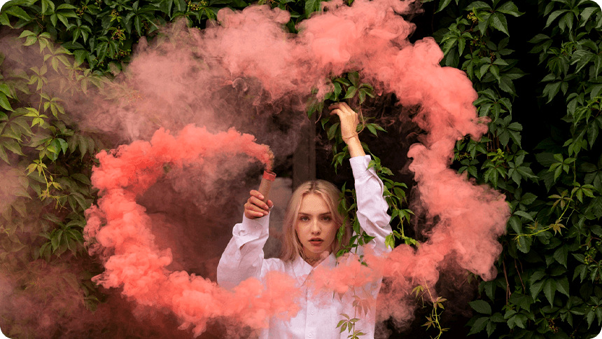 発煙筒のピンクの煙で大きく渦を描く女性